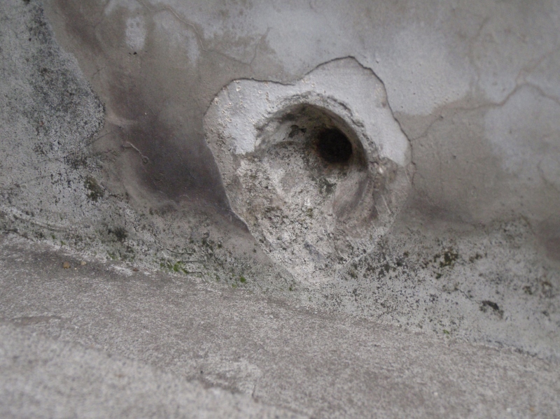 Ｐコンの跡。埋められていたモルタルがきれいに取れている。中央にみえる茶色のものは、コンクリート内部に埋め込まれたセパレーターが錆びているところ。