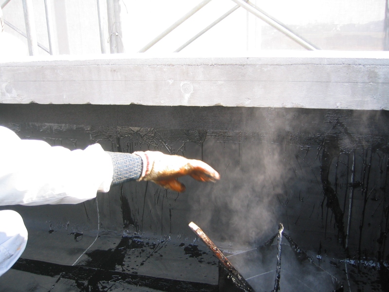 アスファルト防水熱工法。立上り部を施工中。火傷（やけど）の危険がある。