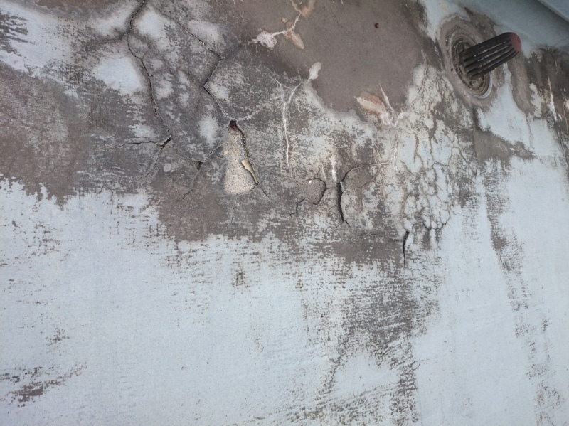 アスファルト防水の上に、セメント系塗膜防水を施工した数年後の様子。黒い箇所は、アスファルト防水の成分がセメント系塗膜防水表面に出てきたものと思われる。